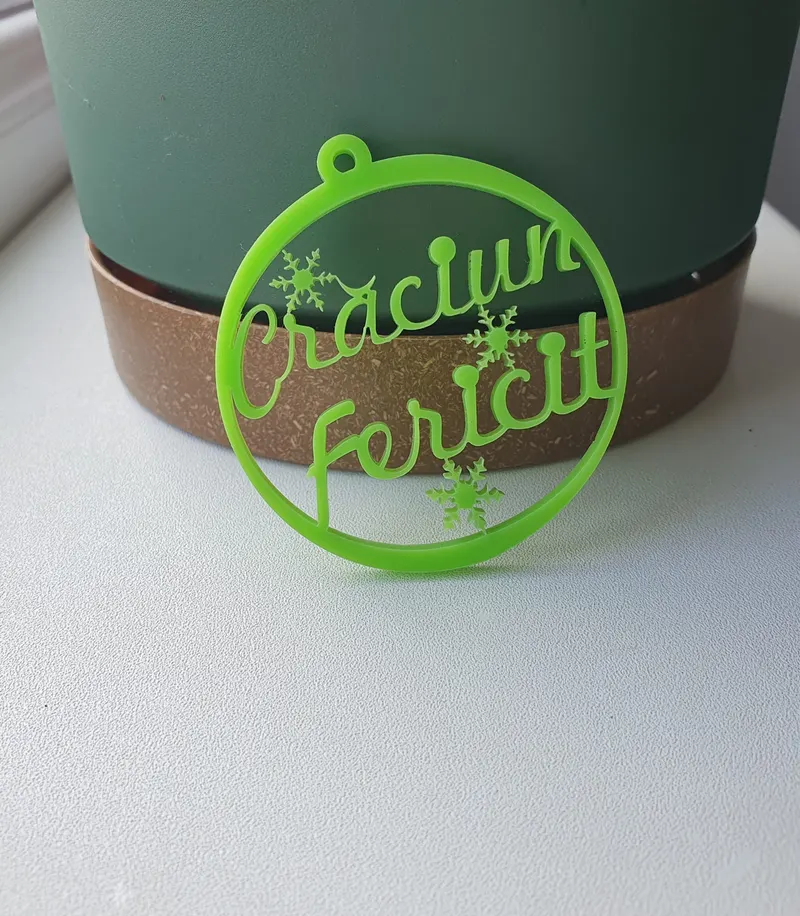 Ornament rotund de Crăciun din plexiglas verde cu textul „Crăciun Fericit” și fulgi de nea, tăiat laser