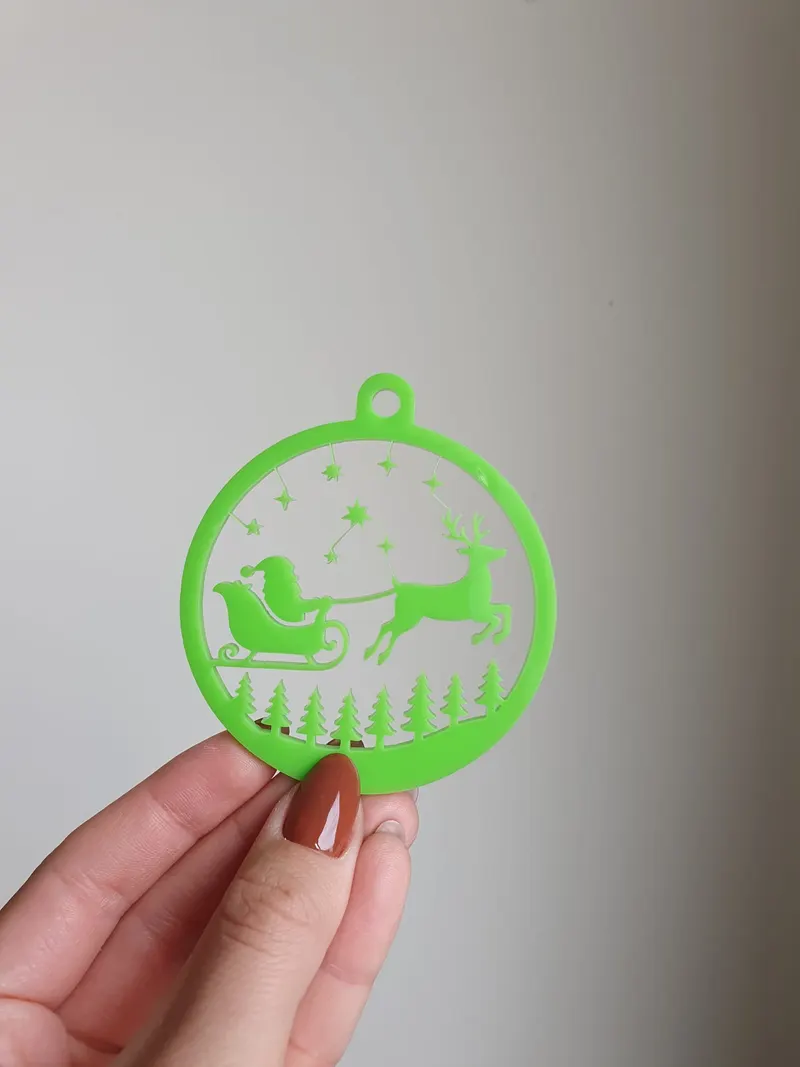 Glob de Crăciun din plexiglas verde cu Moș Crăciun în sanie trasă de un ren, stele și brazi decupați laser