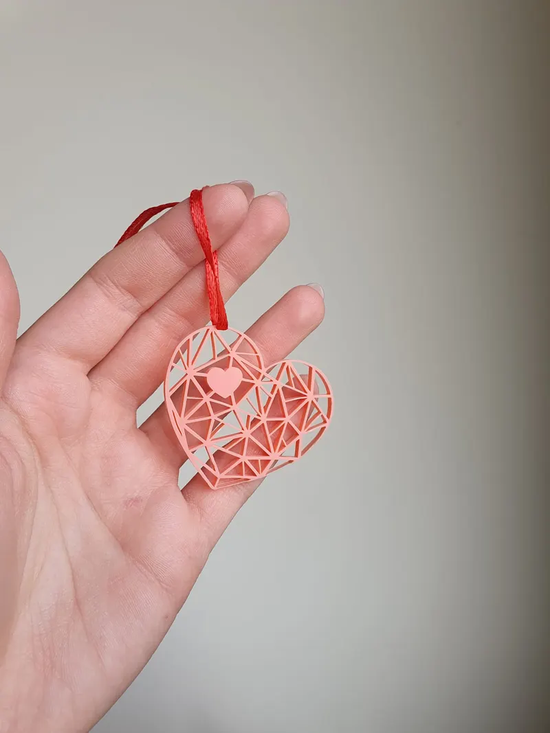 Ornament inimă geometrică din plexiglas roz tăiat laser, agățat cu o panglică roșie